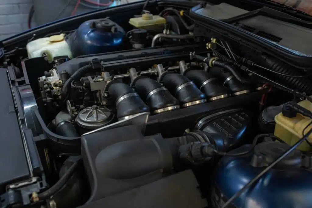 A detailed view of a BMW engine bay, highlighting the individual throttle bodies, intake manifold, and various engine components.
