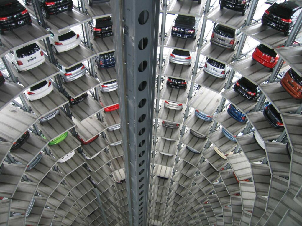 Interior view of a tall, circular automated parking garage, with multiple levels of cars stacked in a vertical tower around a central open shaft.