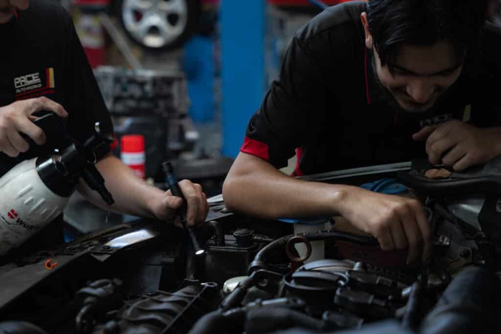 two car mechanics working on car engine