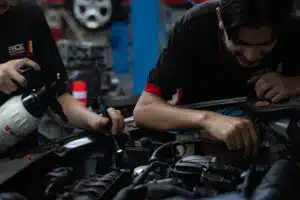 two car mechanics working on car engine