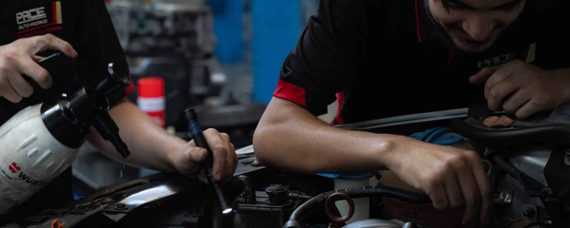 two car mechanics working on car engine