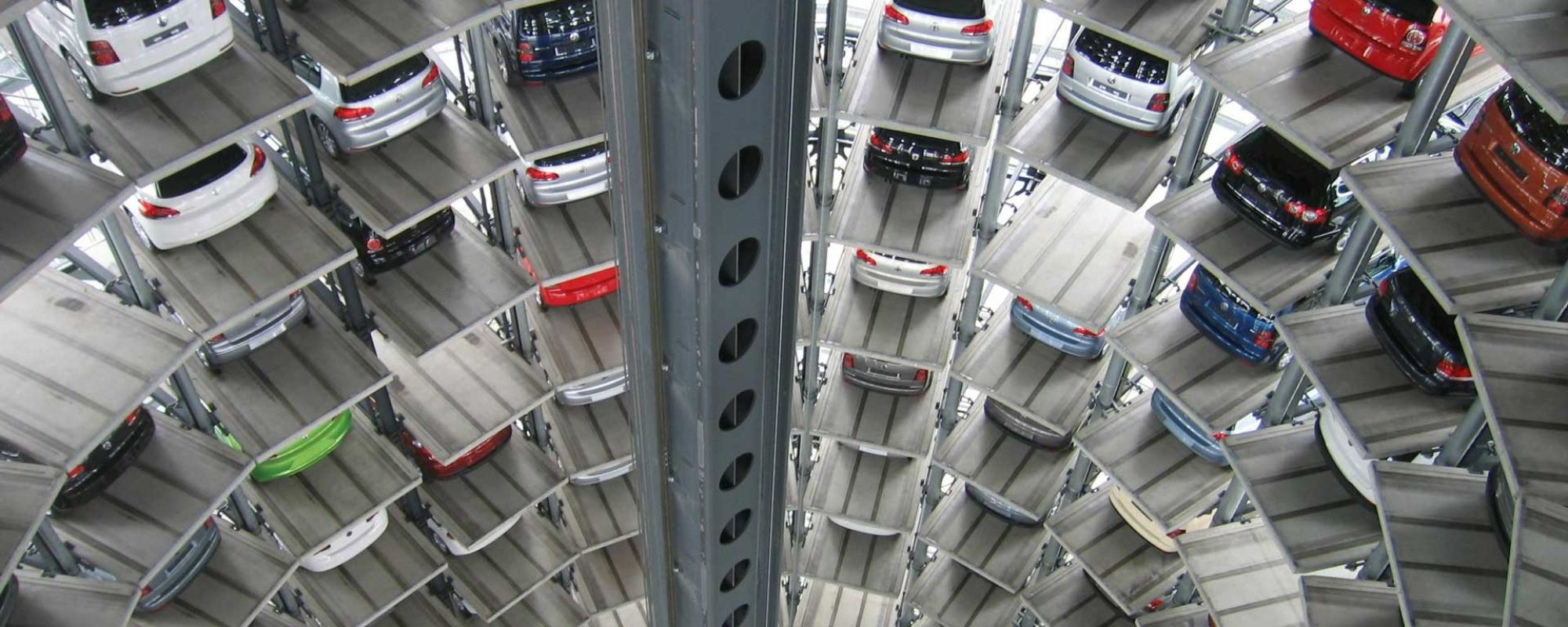 Interior view of a tall, circular automated parking garage, with multiple levels of cars stacked in a vertical tower around a central open shaft.